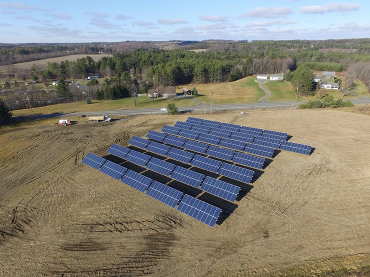 Sunlight glinting off a large community solar array in the middle of a field, symbolizing a bright, clean energy future.