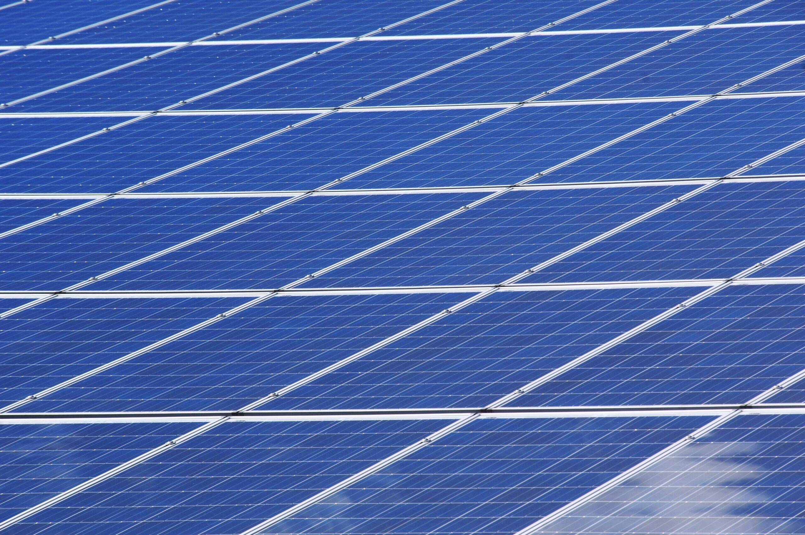 Close-up of a solar panel in a community array, showing the textured surface of individual photovoltaic cells.